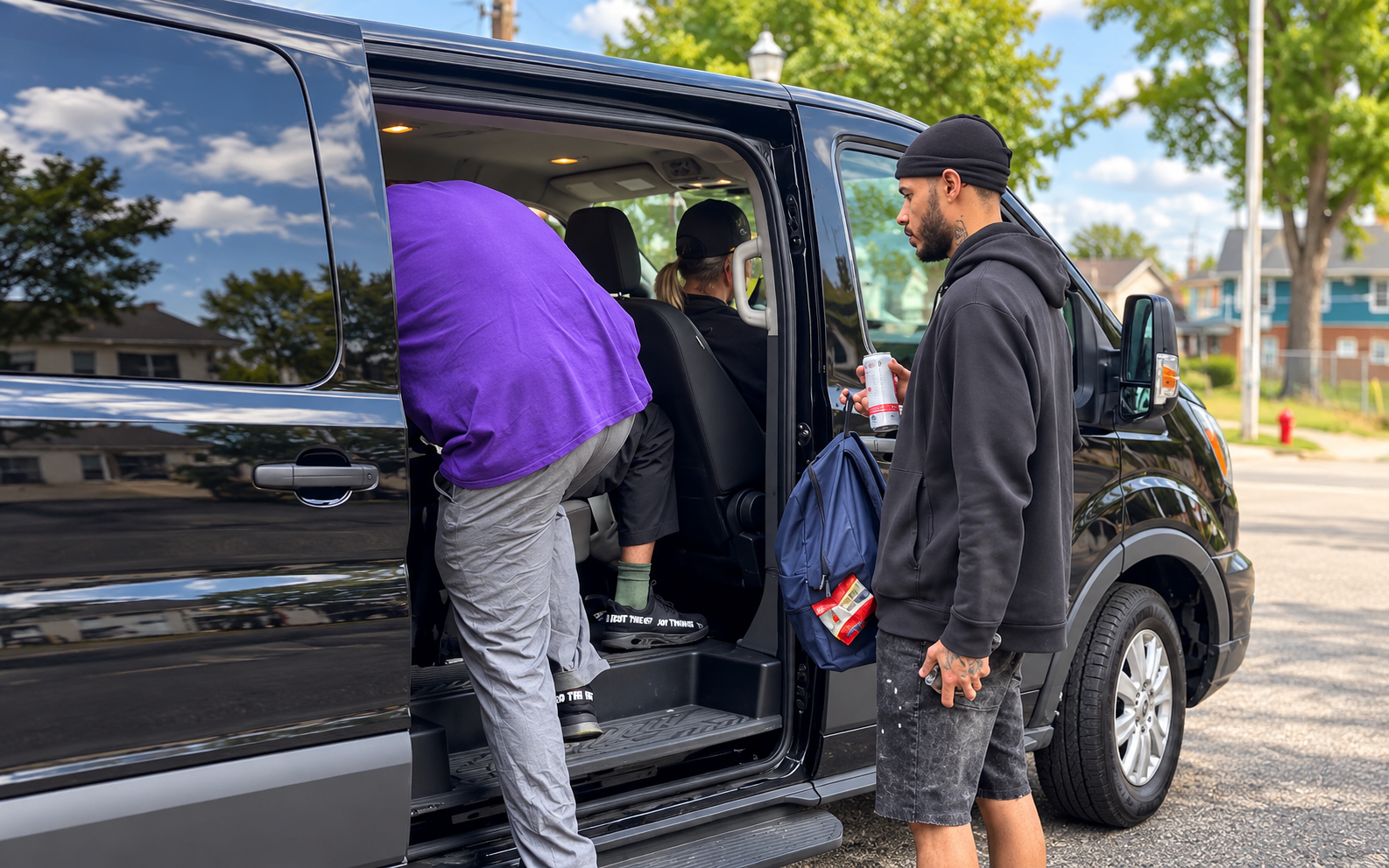 A man in a hoodie holds a drink and backpack, while another enters a black van on a sunny street with trees and houses.