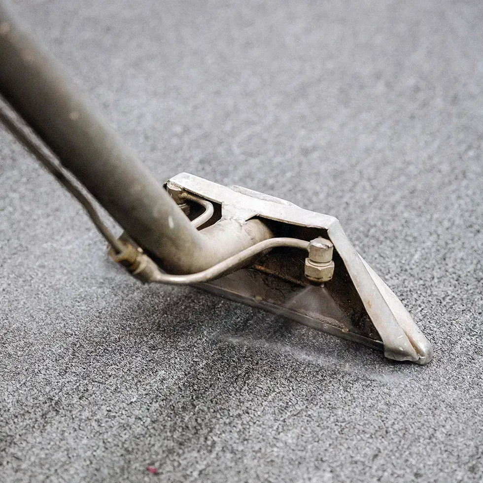 Carpet cleaning tool on gray carpet.
