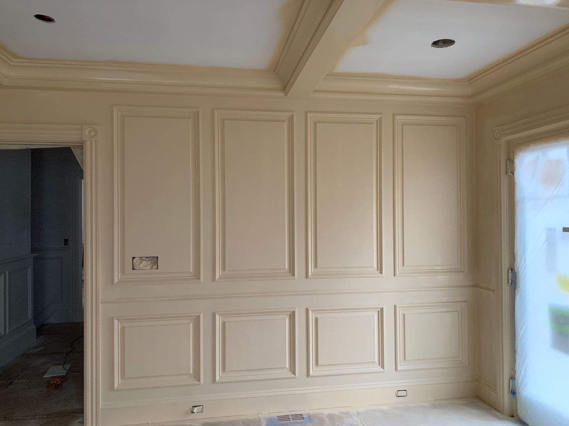 Empty beige paneled room with recessed ceiling lights and a window on the right
