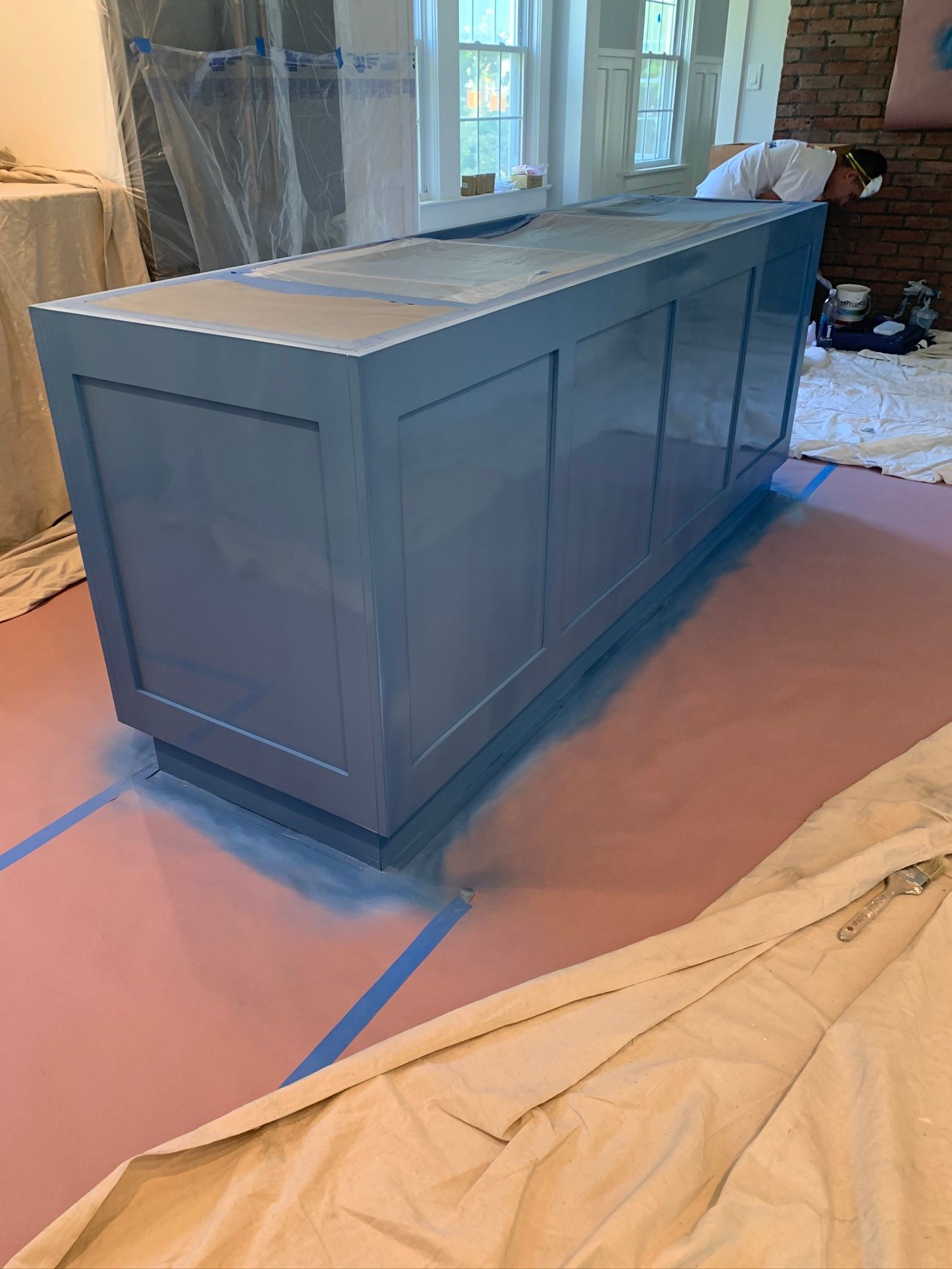 Gray built-in cabinet or island under construction, covered with protective floor paper in a room.