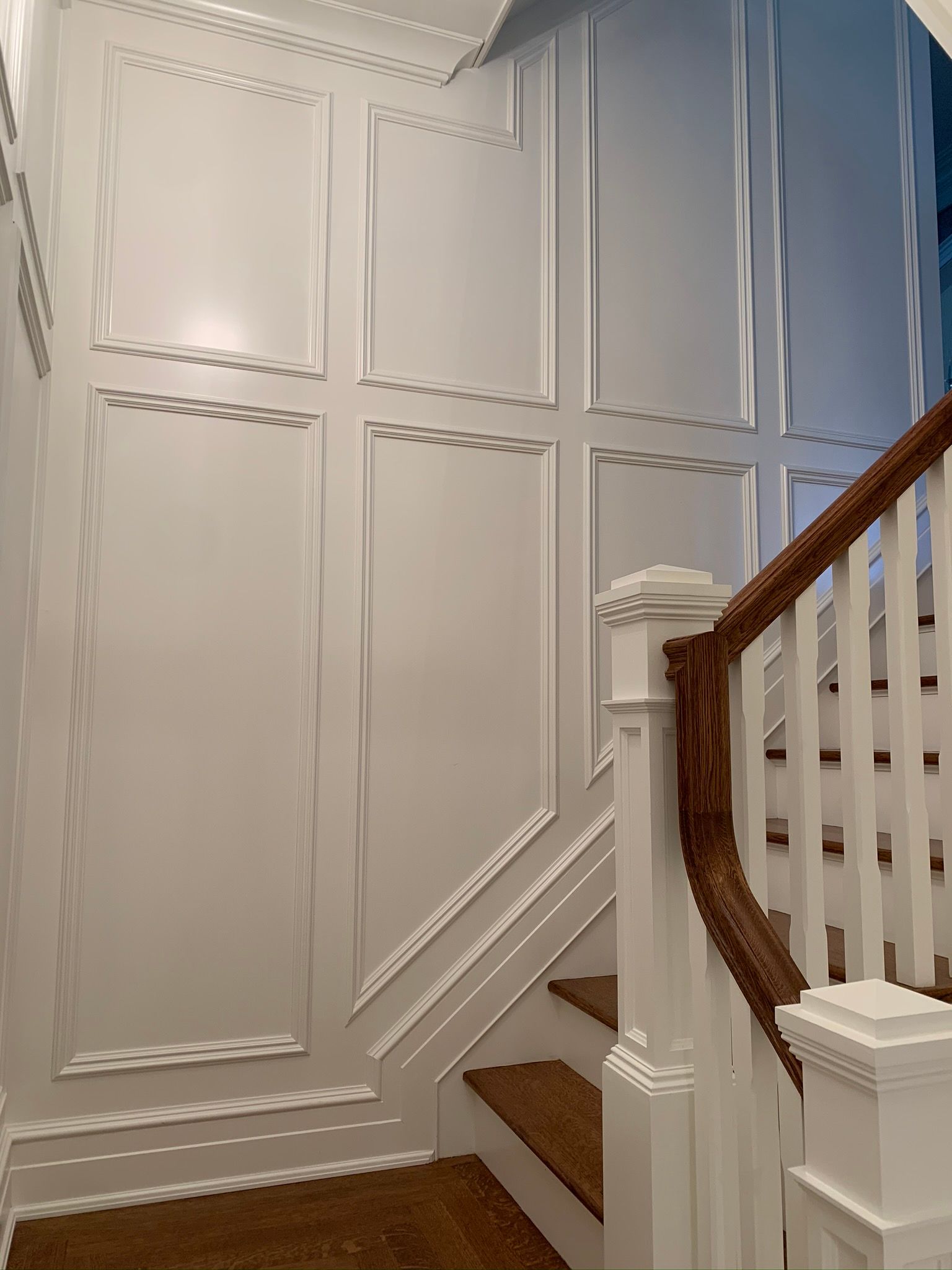 Elegant white staircase with ornate wall paneling and a curved wooden handrail