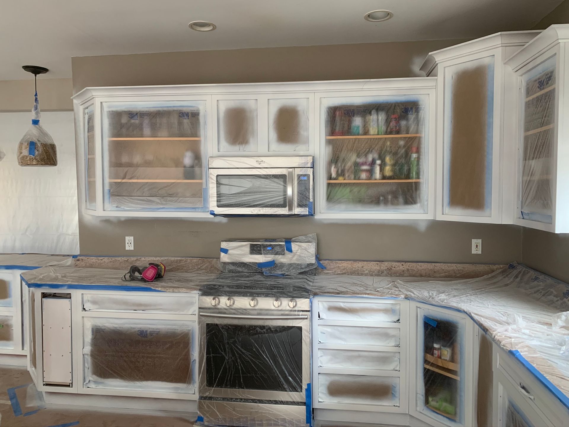Partially renovated kitchen with white cabinets, granite countertops, and appliances installed