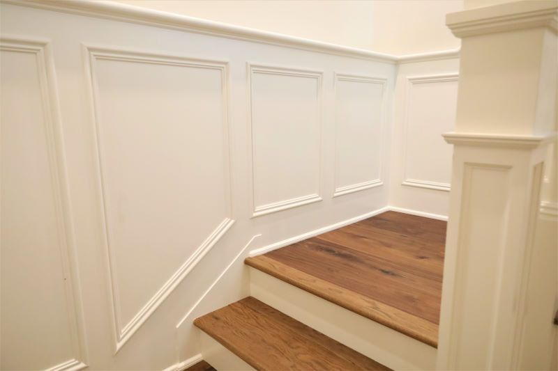 White paneled stairwell with wood steps and landing in a bright interior hallway