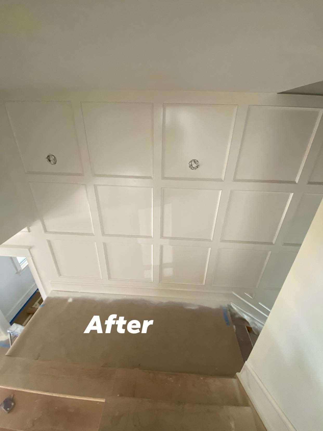 White paneled ceiling or wall with “After” text over a brown floor area, viewed from below
