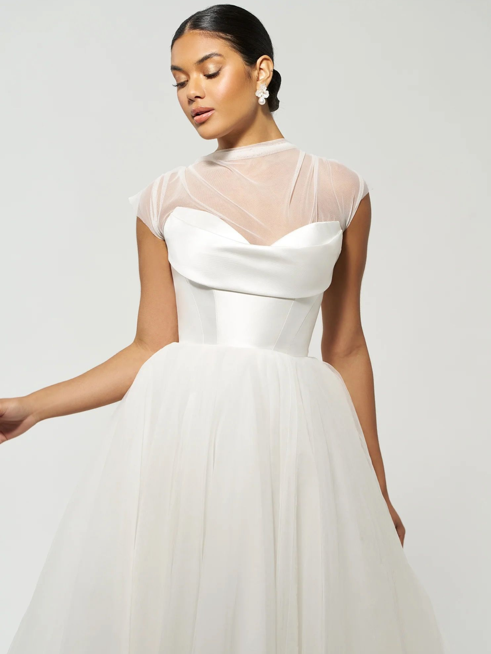 Woman in a white wedding dress with a high-neck lace top and a tulle skirt.