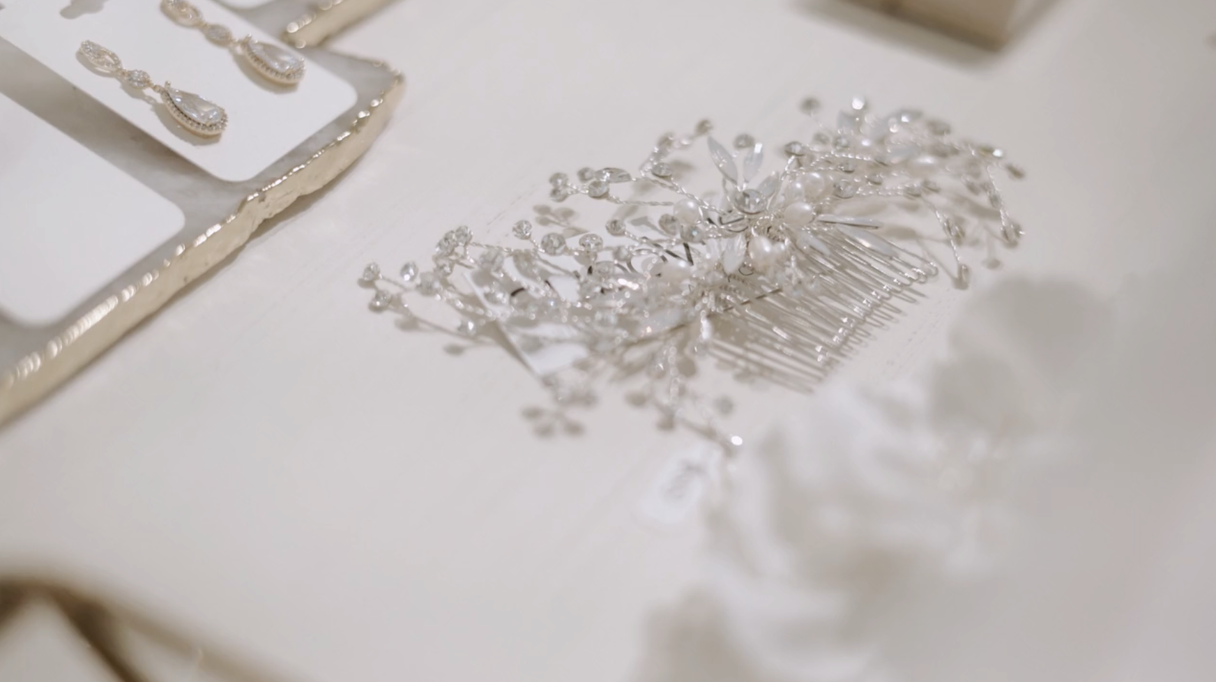 Sparkly silver bridal hair comb and earrings on a white surface.