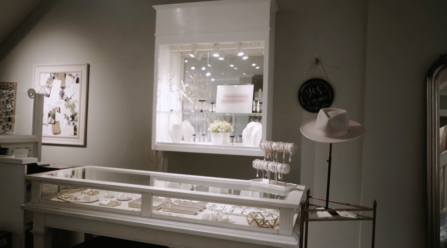 Jewelry store interior with display cases, jewelry, and a hat on a stand.