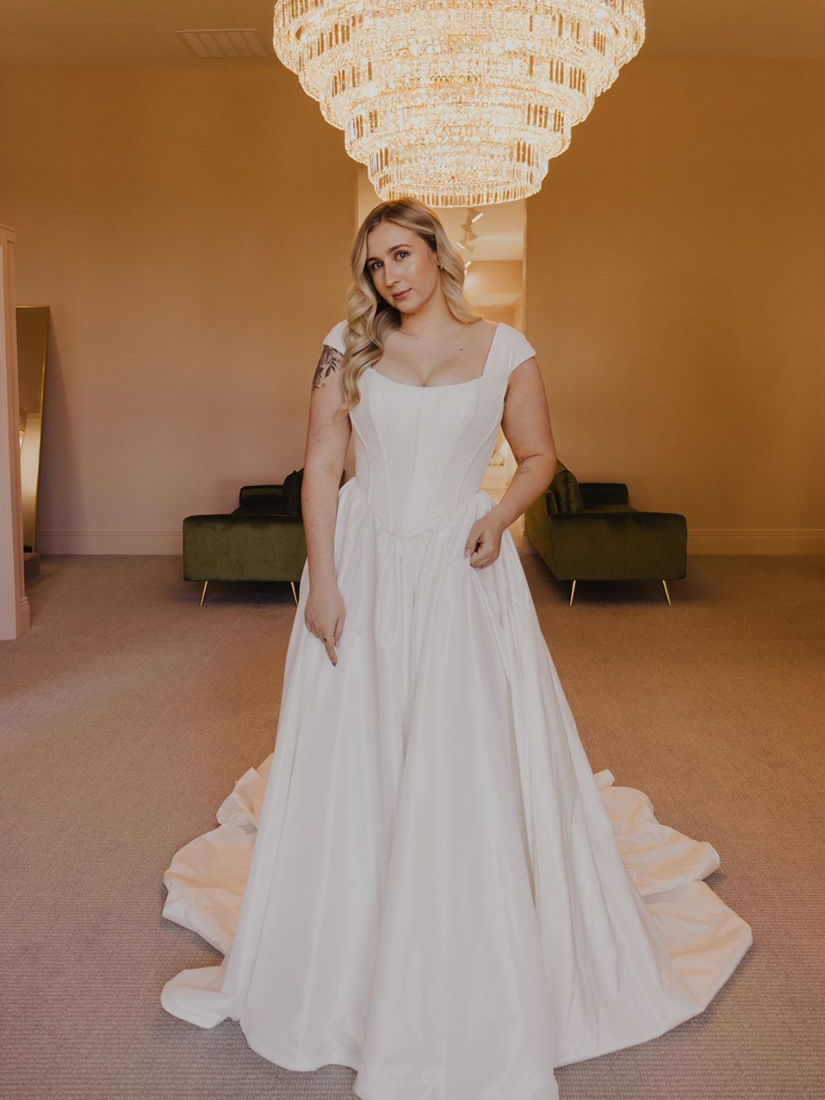 Woman in wedding dress poses in bridal shop.
