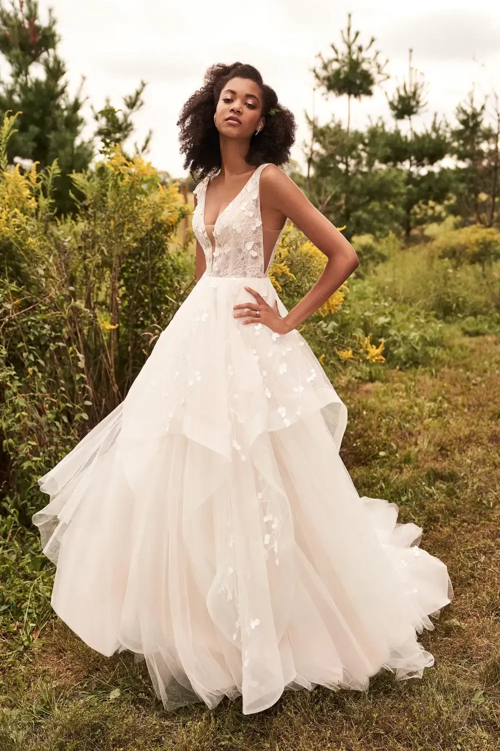 Woman in a flowing white wedding dress poses outdoors.