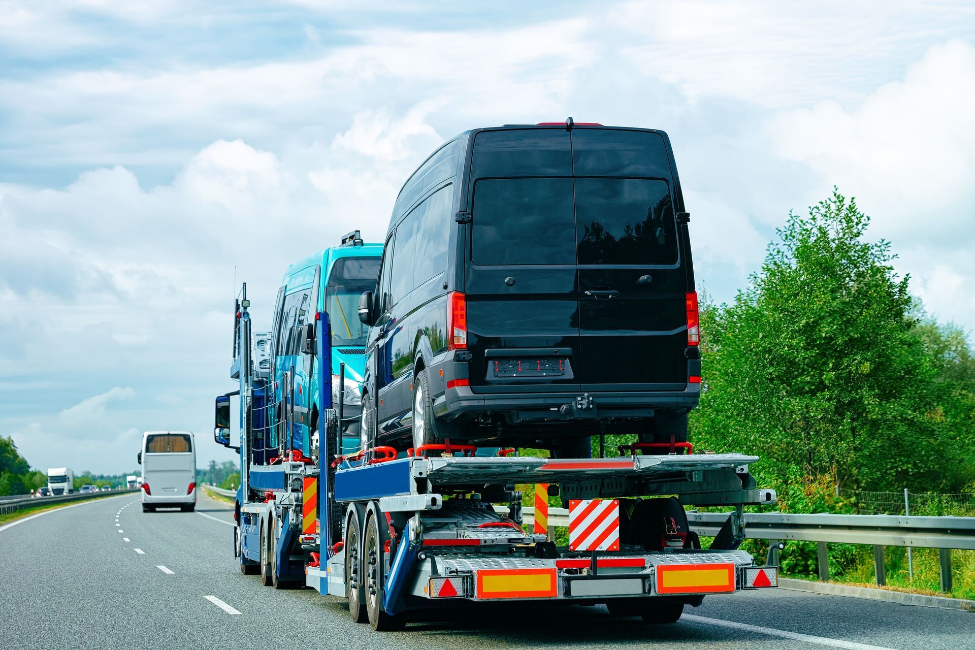 A black van on a car carrier truck driving on a highway.