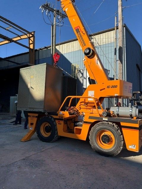 Orange crane loader lifting a large metal container in an industrial yard