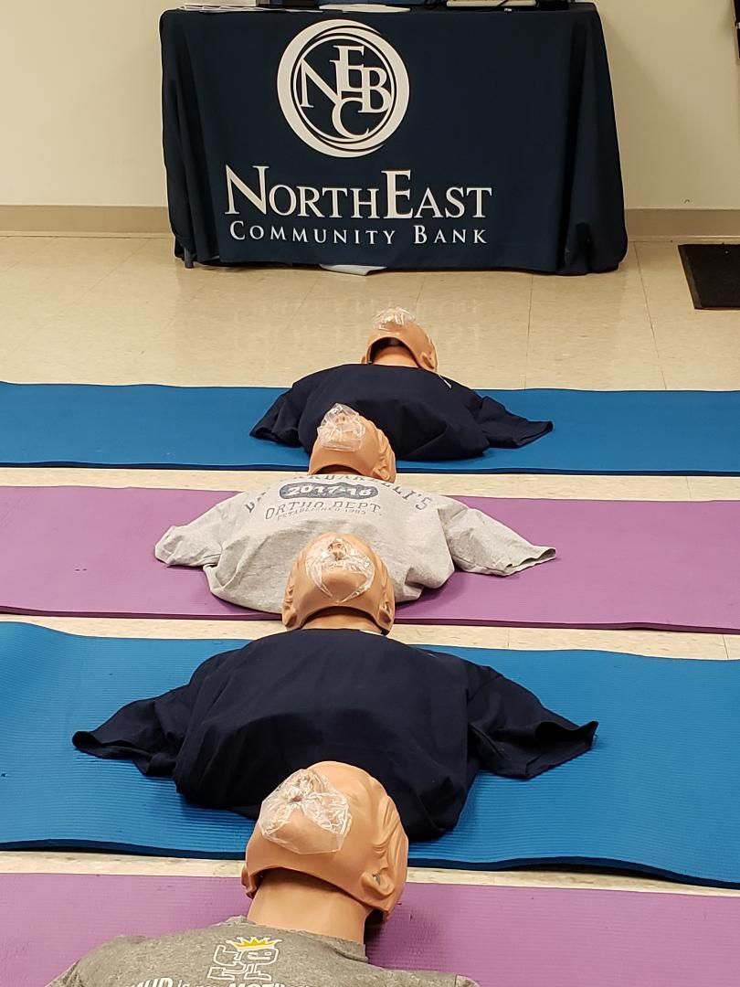 People lying on yoga mats in a row during a fitness class, viewed from behind.