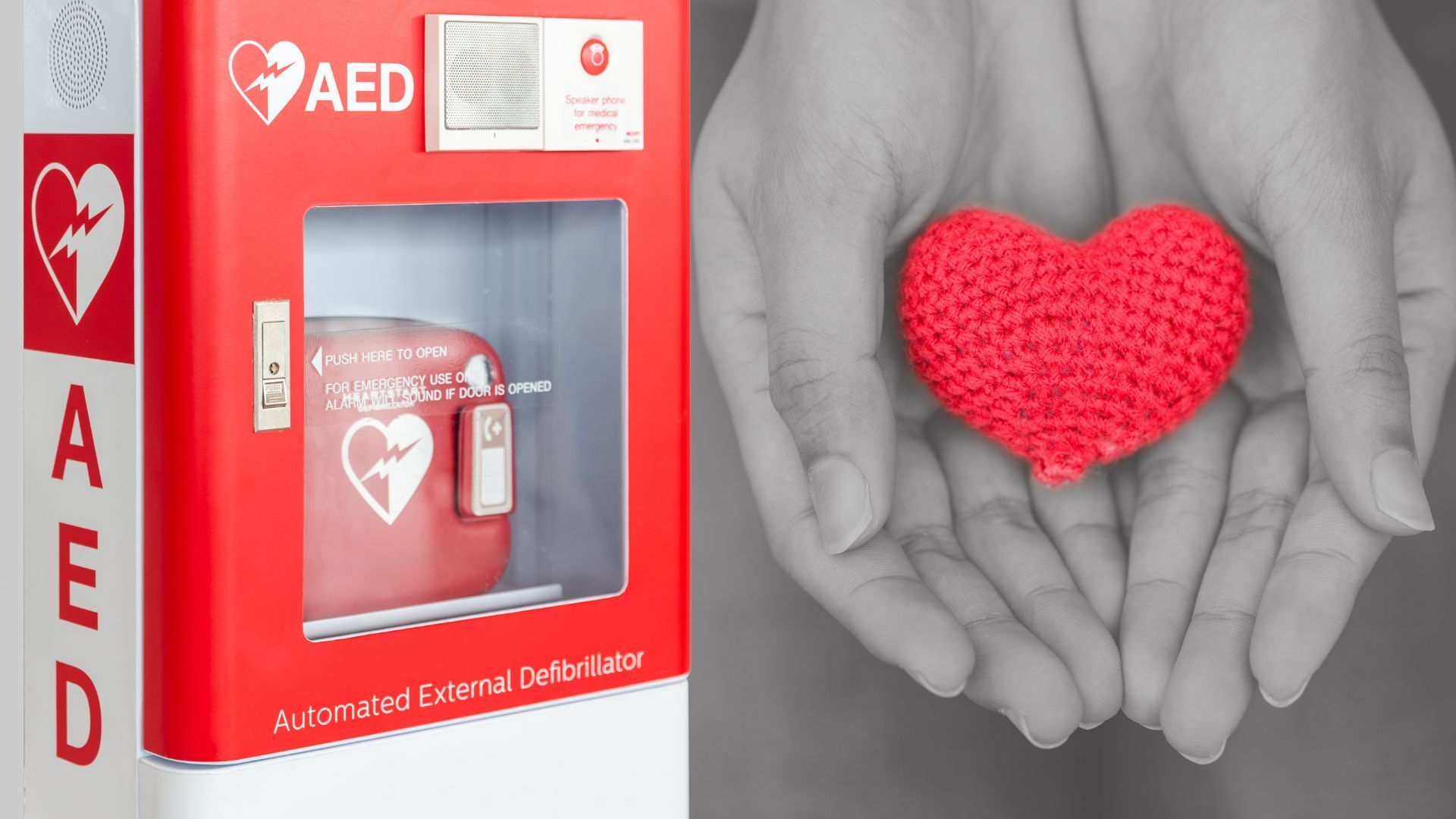 AED cabinet beside grayscale hands holding a red heart shape