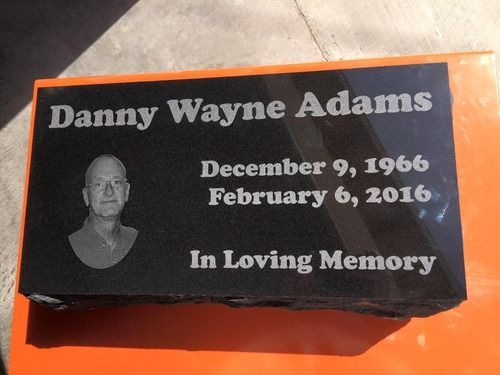 Black memorial plaque for Danny Wayne Adams with dates, “In Loving Memory,” and a small portrait photo.