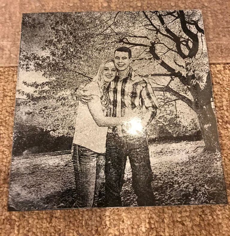 A black-and-white portrait of two people standing together outdoors beside a tree.