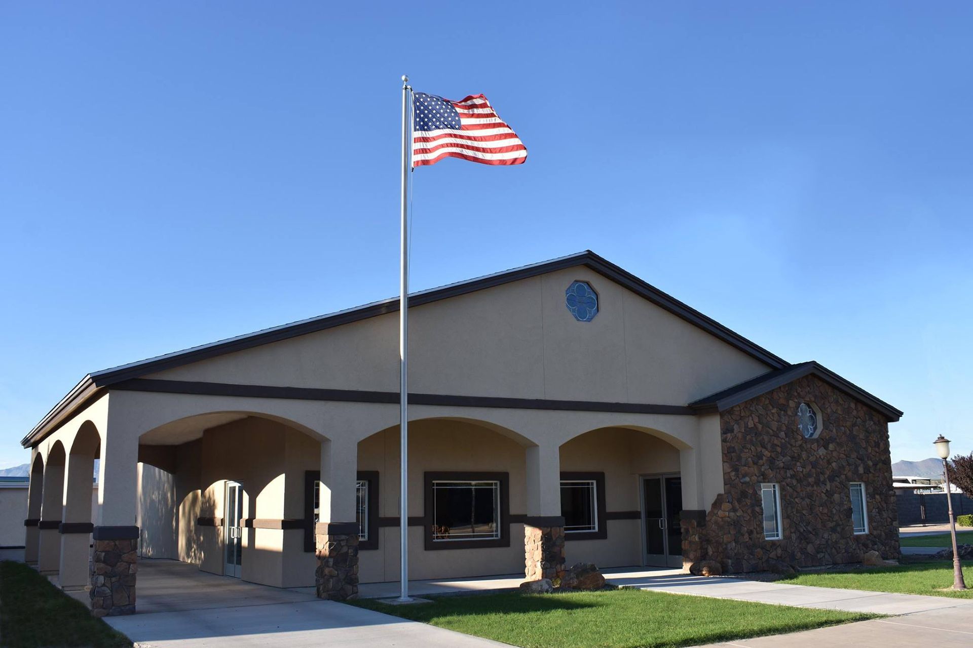 Small civic building with an American flag flying in front on a sunny day