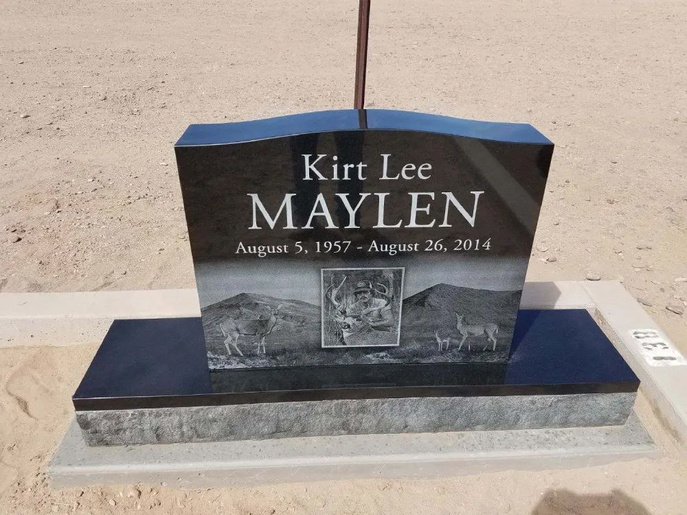 Black granite grave marker with blue cap, engraved “Kirt Lee MAYLEN” and dates, set on a stone base