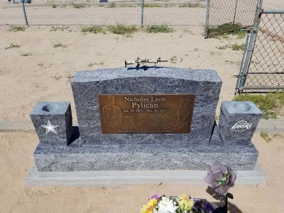 Granite memorial bench with bronze plaque and star emblems in a fenced cemetery plot
