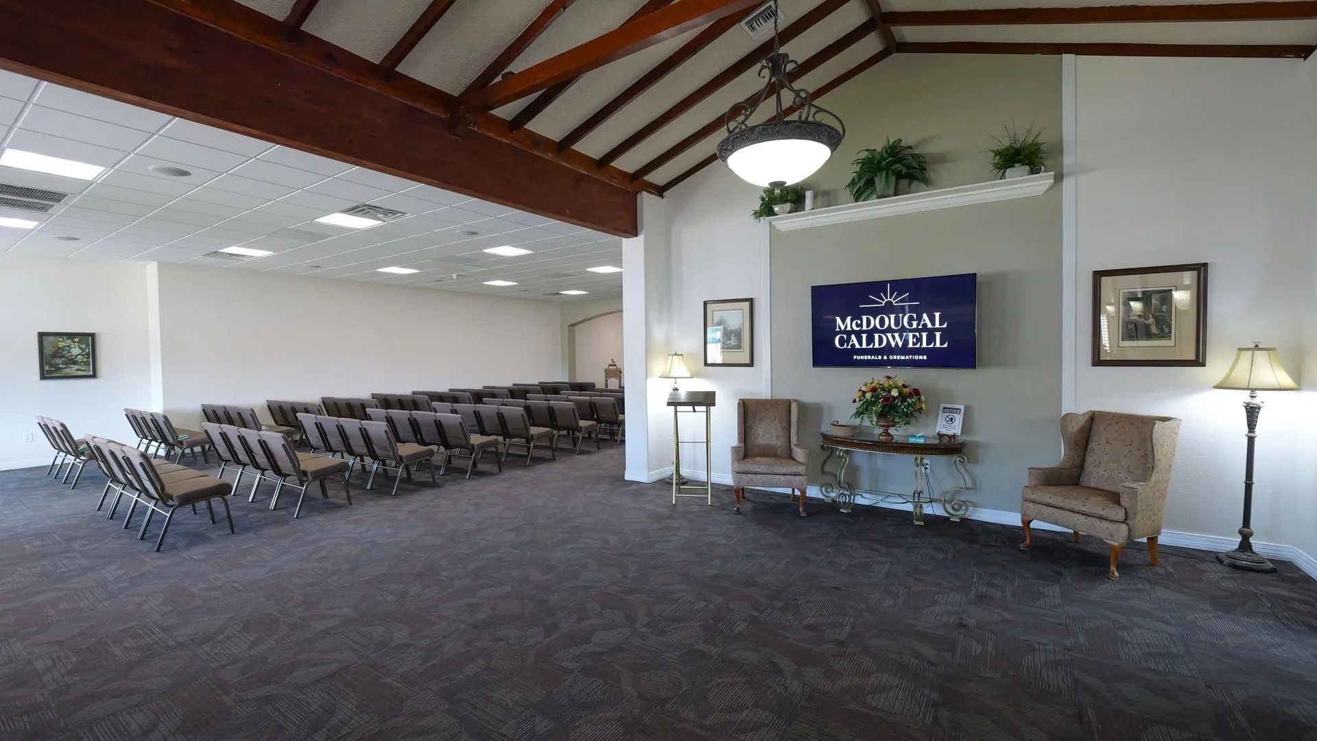 Empty chapel-like room with rows of chairs, a central display, and a high wooden ceiling