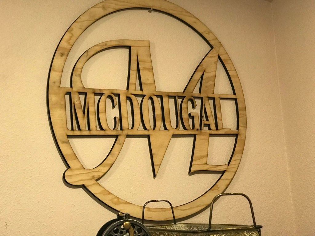 Wooden wall sign with the word “MCDONALD” inside a circular logo on a beige wall.