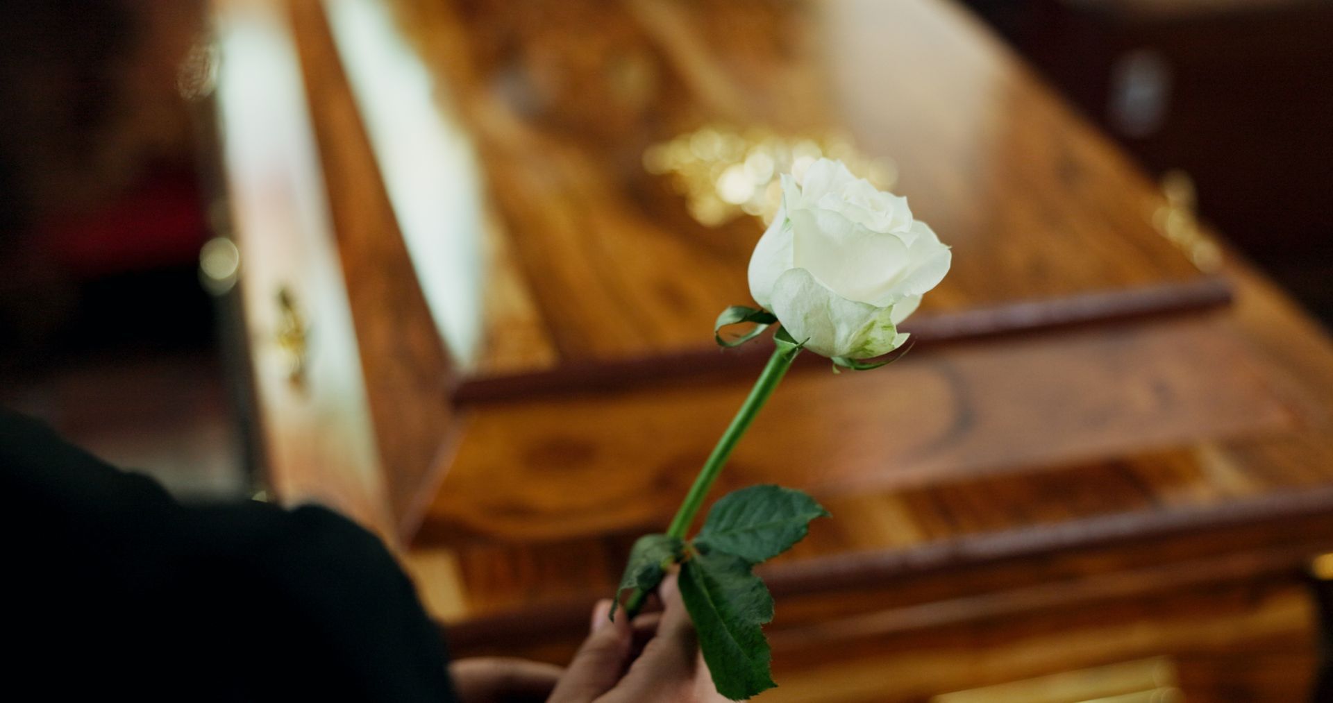 Mourners carry a wooden casket with white flowers at a funeral procession