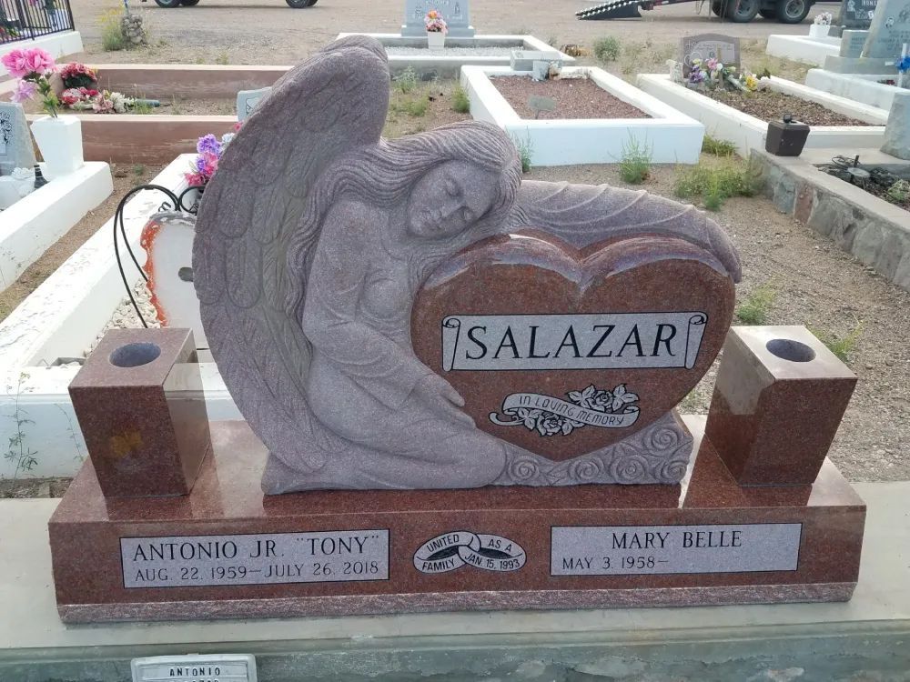 Heart-shaped gravestone with angel sculpture and engraved names in a cemetery