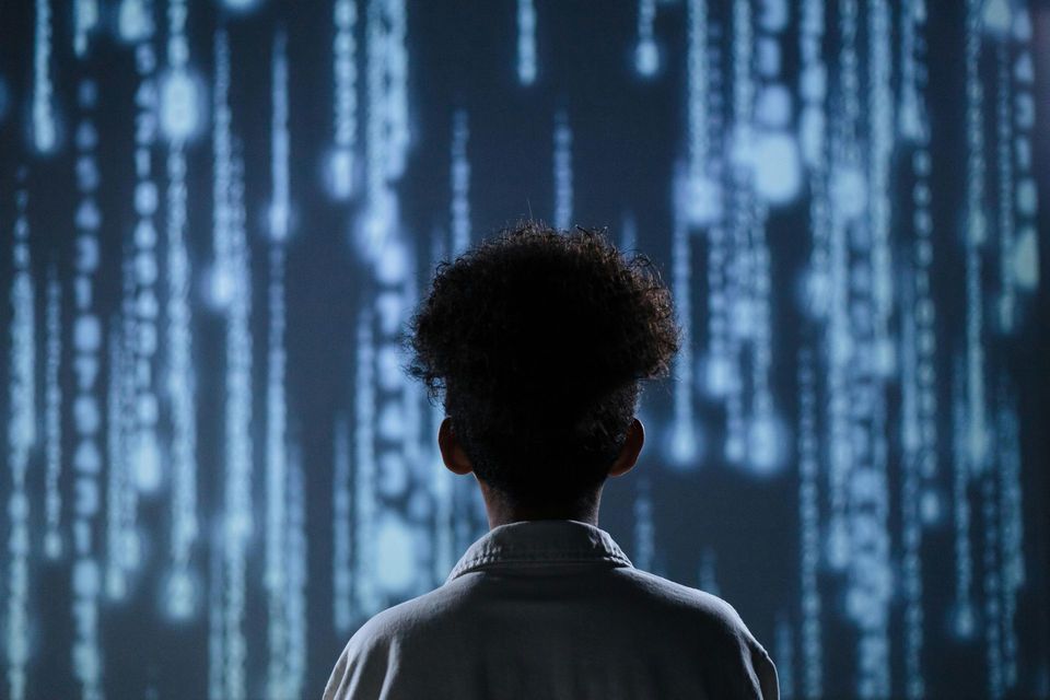 Person facing a screen displaying a matrix of blue digital data, with a soft blur in the background.
