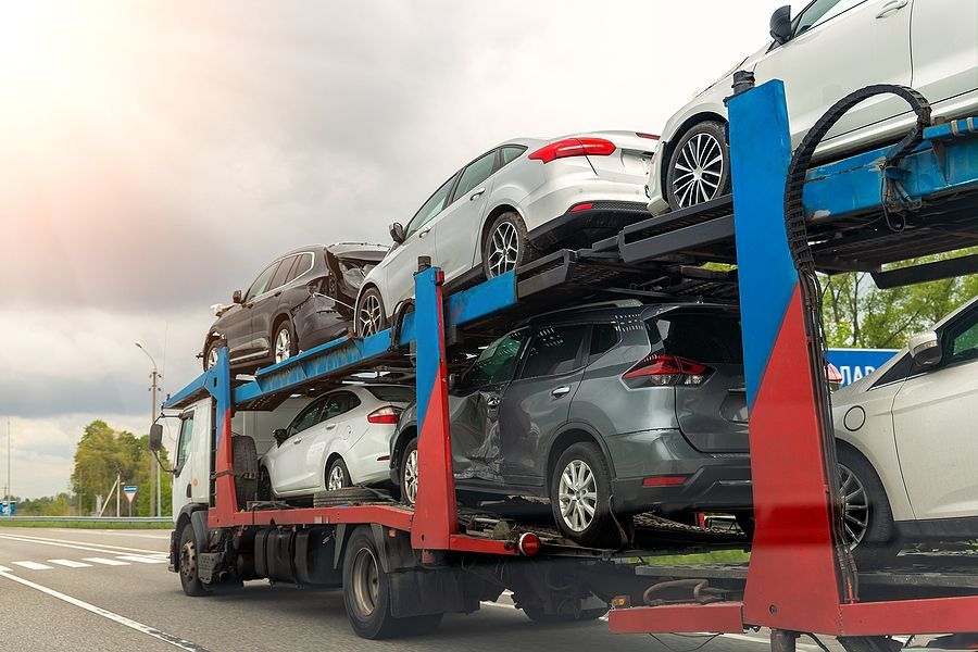 A tow truck is carrying a bunch of cars on a highway.