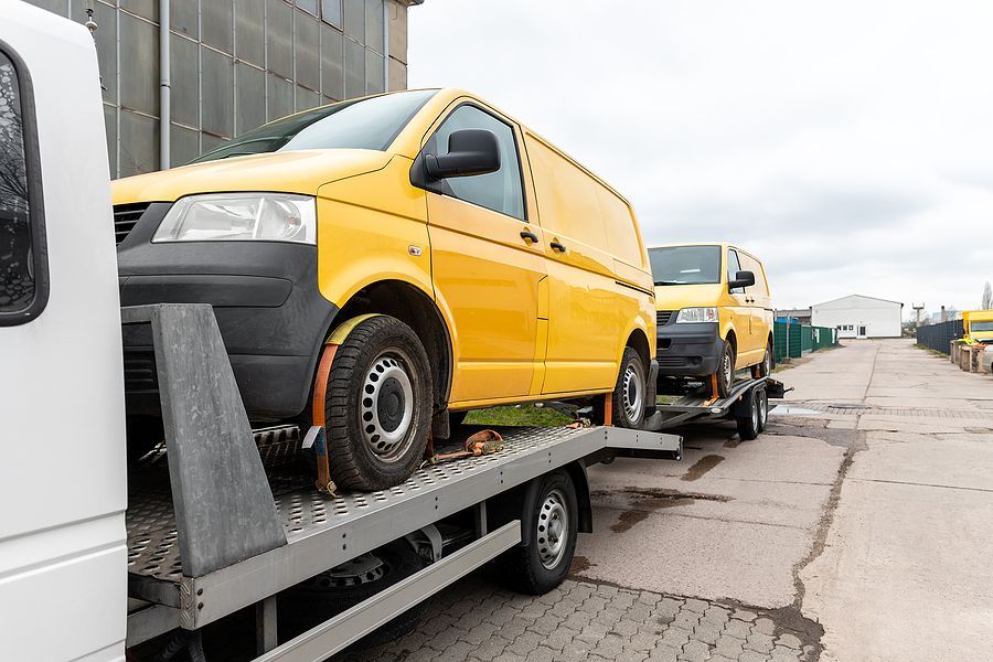 A yellow van is being towed by a tow truck