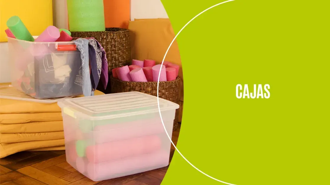 Cajas de plástico para guardar cosas y toallas dobladas sobre una mesa, con la palabra “CAJAS” sobre un fondo verde.