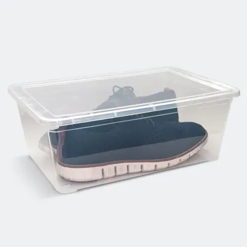Caja de almacenamiento de plástico transparente que contiene un par de zapatillas negras con suelas blancas.