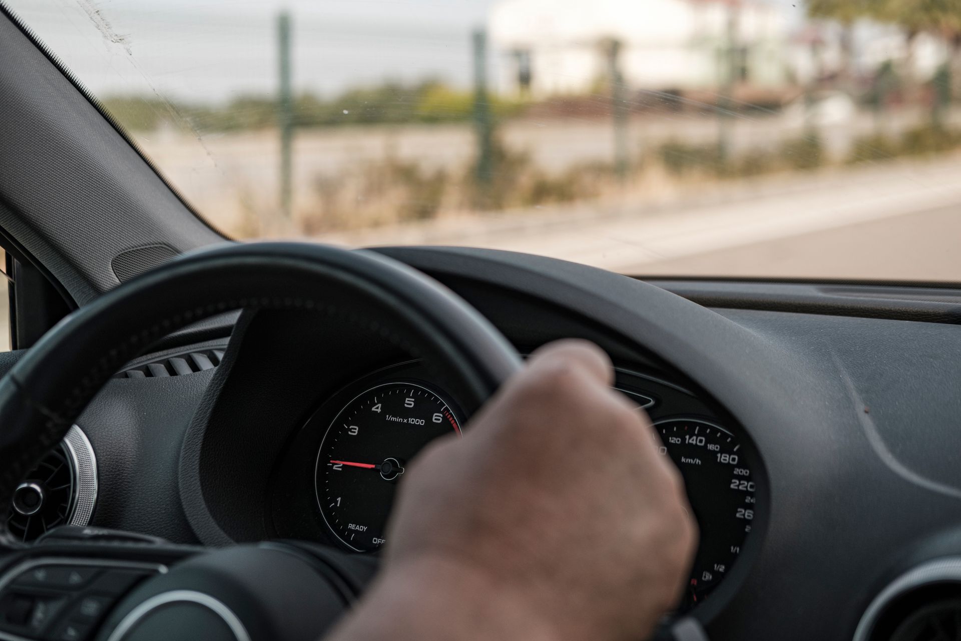 Older adult driving a car with hands on the steering wheel during a road trip.