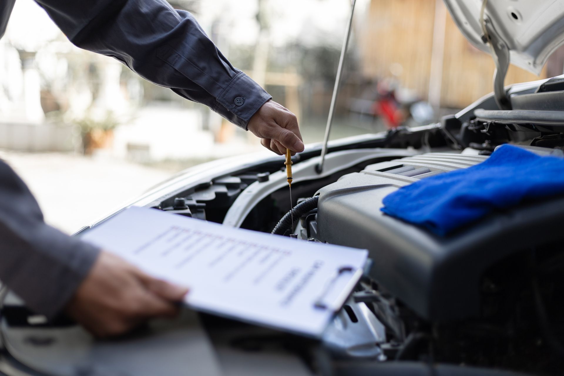 A mechanic with a checklist in hand, checks the car and engine oil as part of Audi repair services.