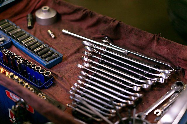 Mechanic's tools: wrenches, sockets, and other tools arranged on a red shop towel.