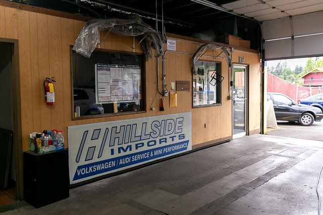 Hillside Imports auto shop entrance with sign, counter, windows, and fire extinguisher.
