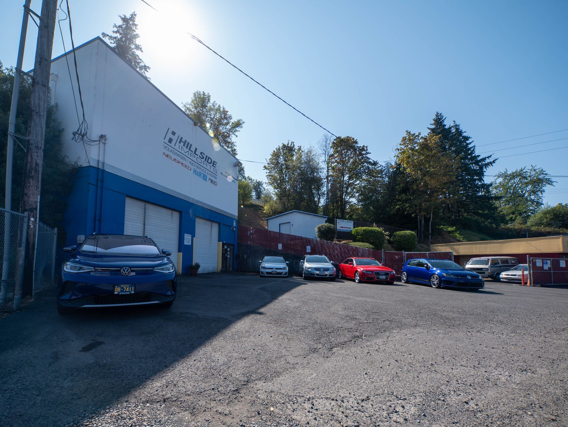 Cars parked in front of a blue and white building, sunny day.