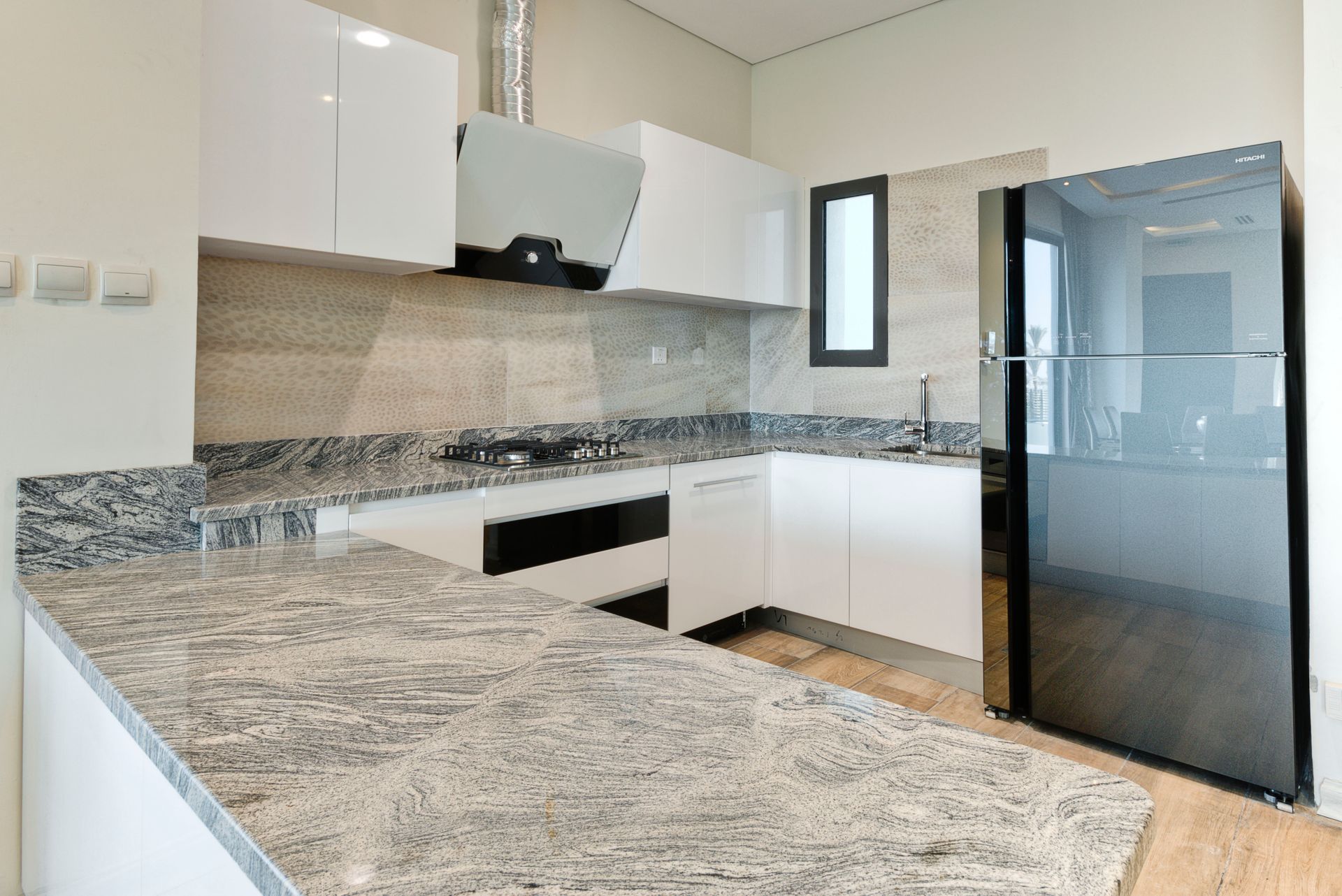 Modern white kitchen with granite countertops, stainless steel appliances.