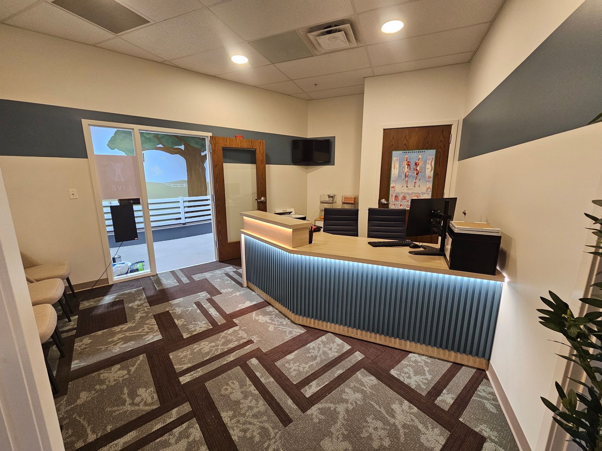 Reception area with desk, blue curtain, carpet, and an open door. New Albany commercial interior painting project. 