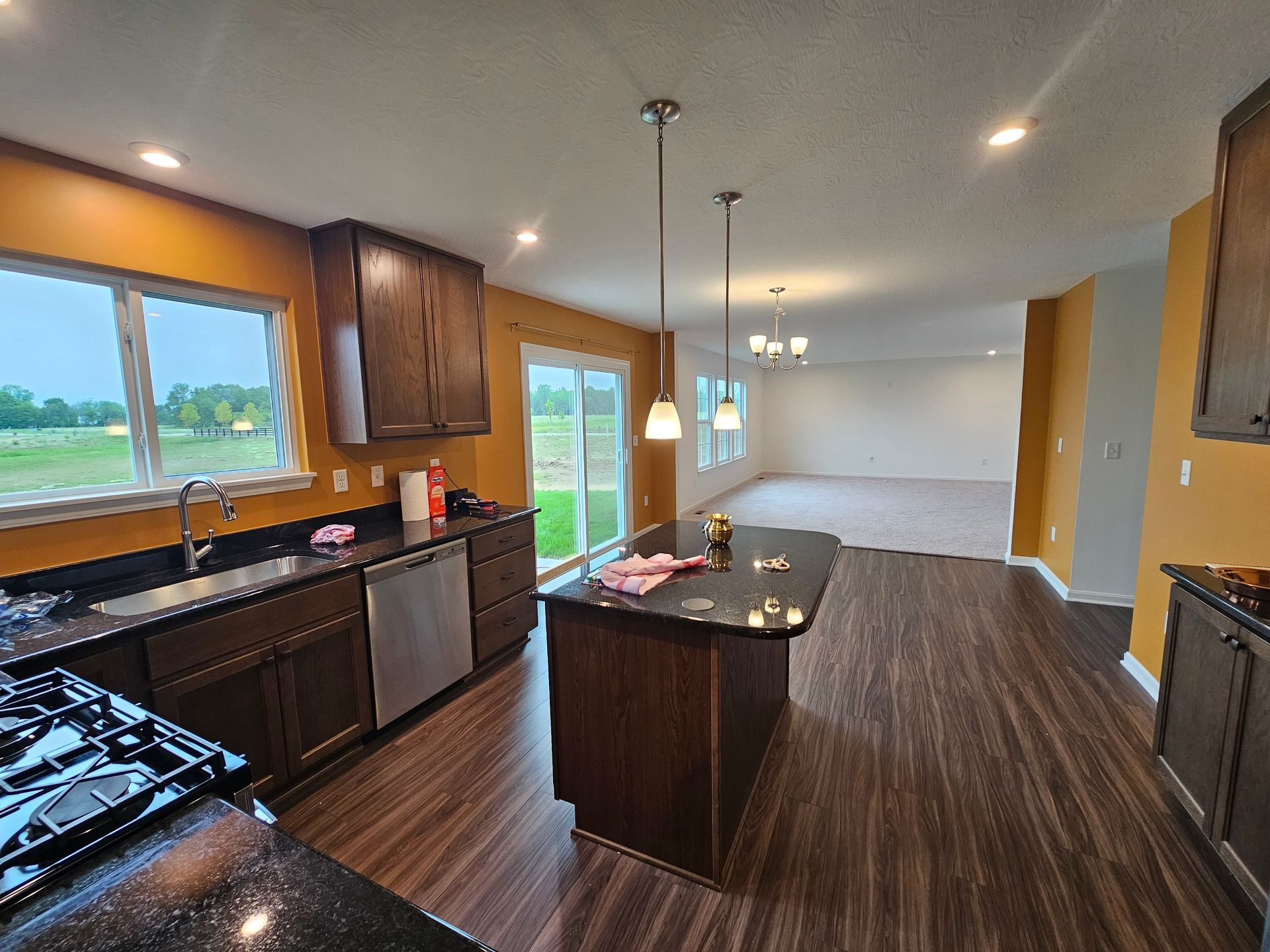 Modern kitchen with dark wood cabinets, island, and flooring, golden walls. Powel interior painting project. 