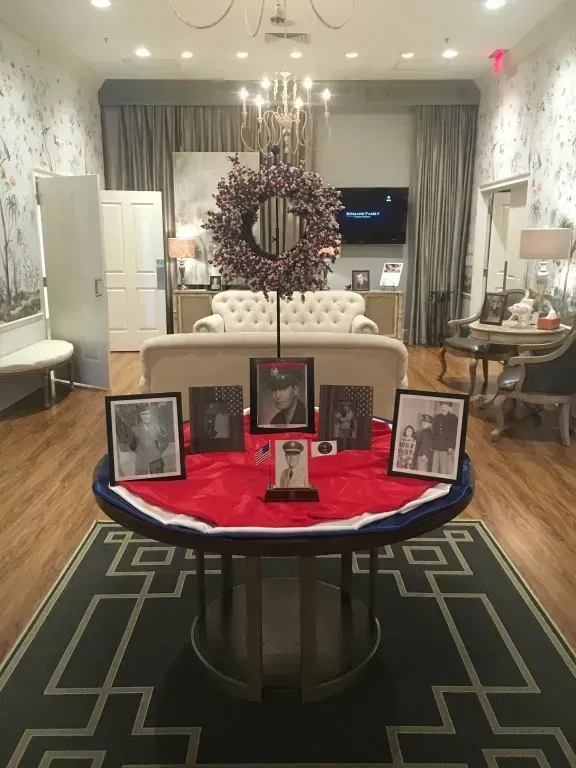 Memorial display with framed photos and candles on a red cloth in a decorated living room