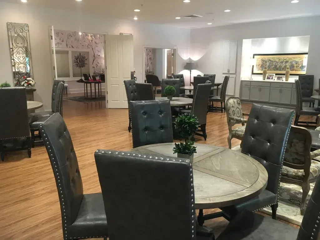Modern dining room with black chairs, round glass tables, and pendant lighting on hardwood floors
