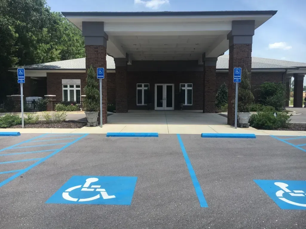 Accessible parking spaces in front of a building entrance with blue handicap markings and signs