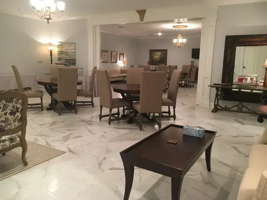 Elegant beige lounge with chandeliers, plush chairs, coffee tables, and marble tile flooring