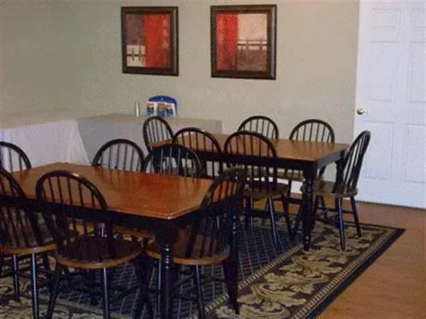 Dining room with a wooden table, black chairs, wall art, and a patterned rug.