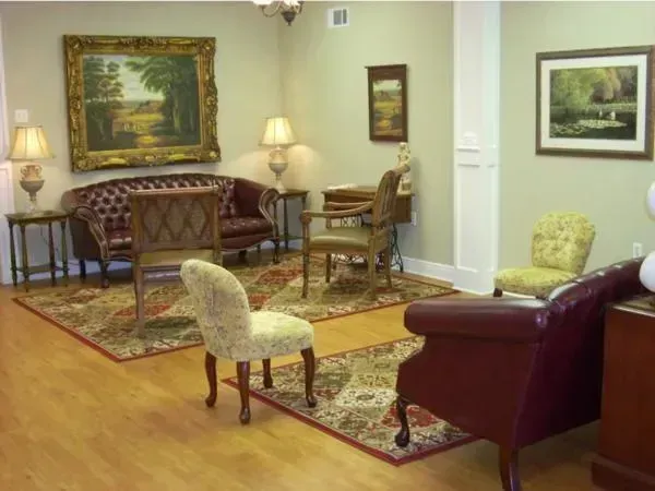Elegant waiting room with patterned rugs, chairs, a sofa, and framed paintings on cream walls