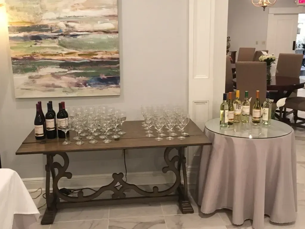 Wine-and-glass display on a table and round cocktail table in an indoor event space
