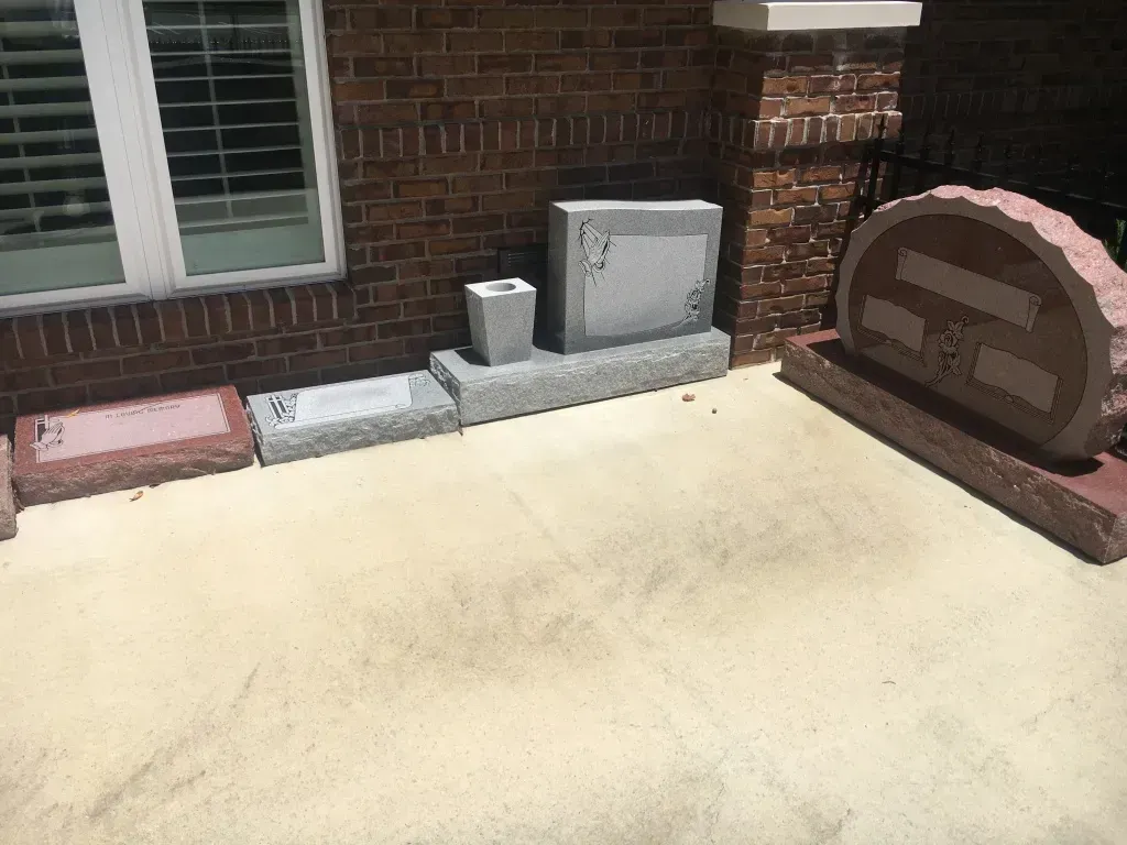 Brick patio with a white window, utility boxes, and a curved stone fire pit or planter along the wall