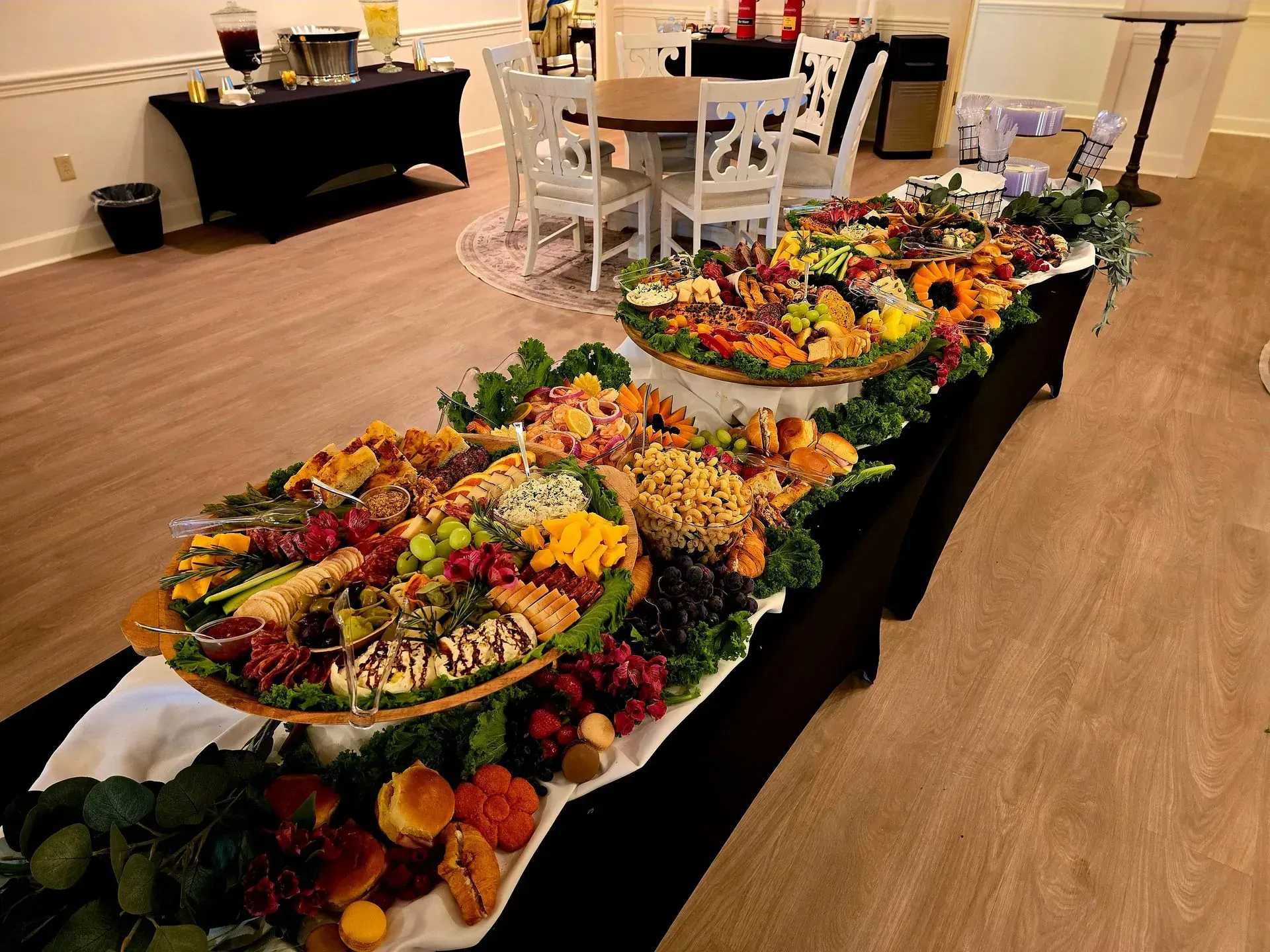 Long buffet table with colorful salads and fruit platters in a bright event hall