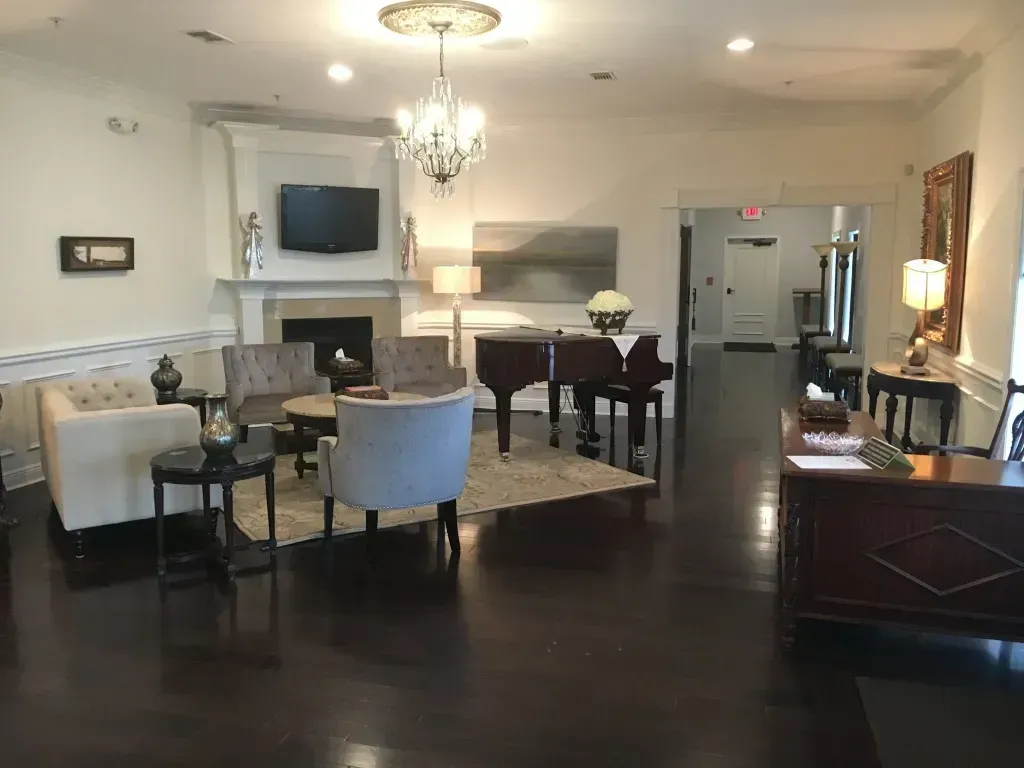 Elegant hotel lobby with seating, chandelier, fireplace, and dark wood flooring