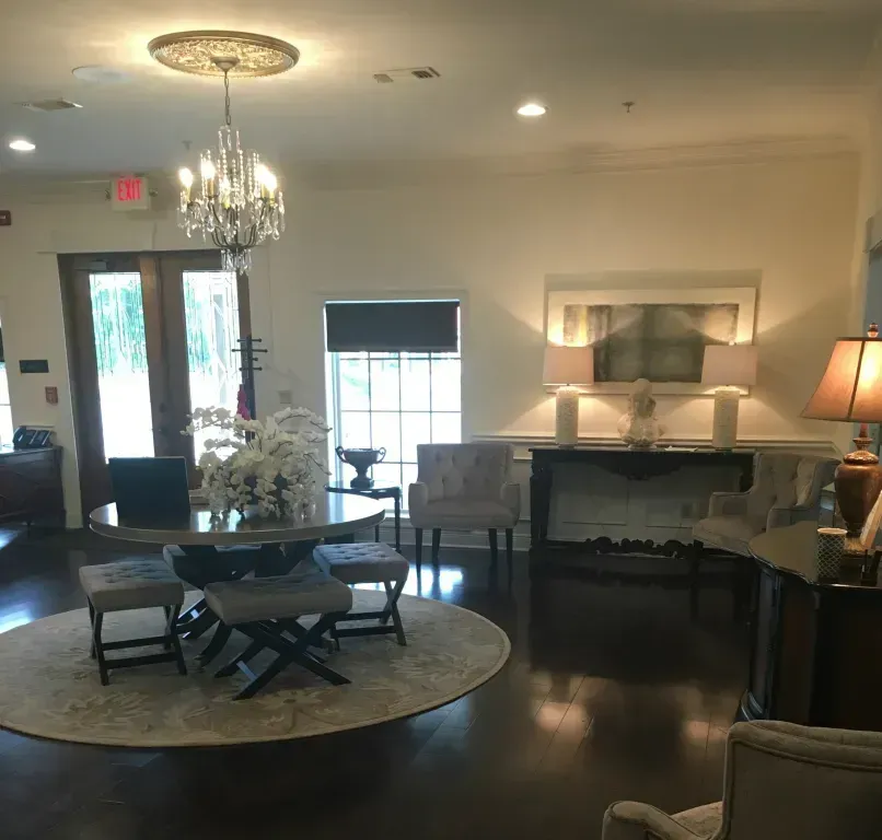 Elegant living room with chandelier, dark wood floors, round coffee table, and fireplace with lamp.